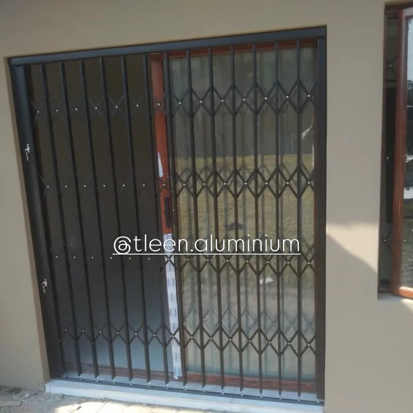 Charcoal trellis security gate across a doorway at dusk