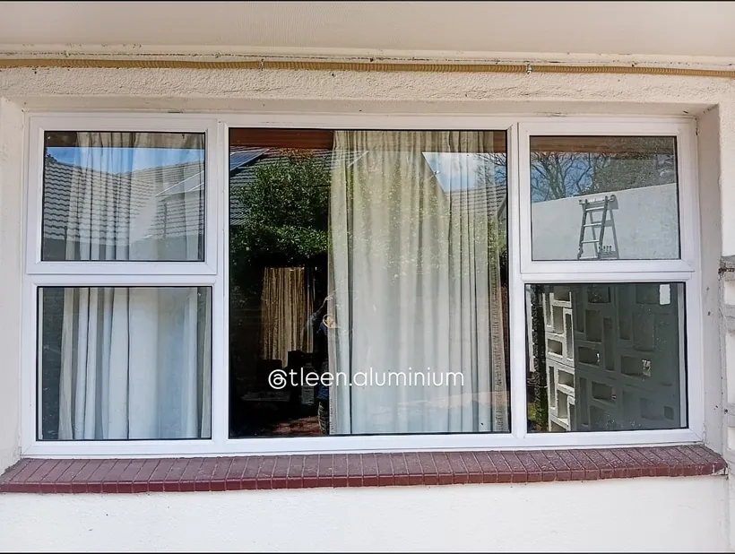 White aluminium top-hung window replacing an older frame